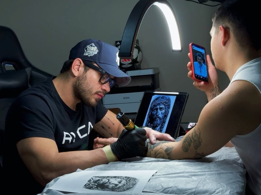 Tatuador Edward Sánchez trabajando en un diseño de tatuaje en el brazo de un cliente
